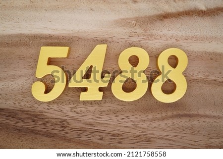Wooden Arabic numerals 5488 painted in gold on a dark brown and white patterned plank background.