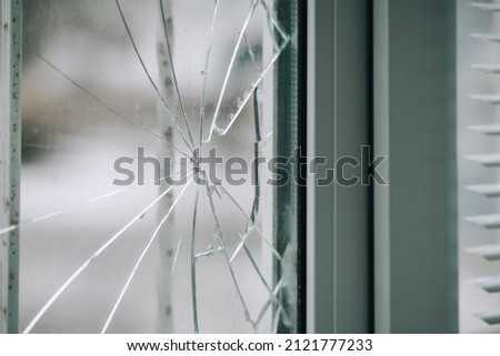 Glass broken by hooligans in a metal-plastic window, close-up. Royalty-Free Stock Photo #2121777233