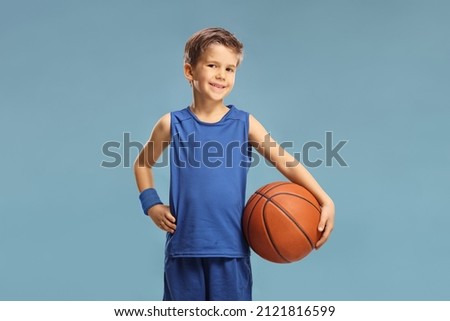 Boy in a blue jersey holding a basketball isolated on blue background