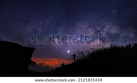 Night time long exposure landscape photography. The milky way, A photography standing  and sitting in a high place looking up in wonder to the Milky Way galaxy, photo composite, nois, grain picture.