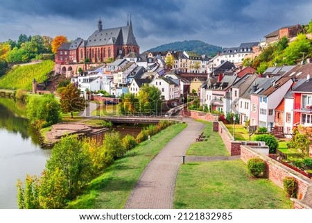 Saarburg, Germany. Idyllic city on Saar River with St. Laurentius church, beautiful autumn sunlight. Royalty-Free Stock Photo #2121832985