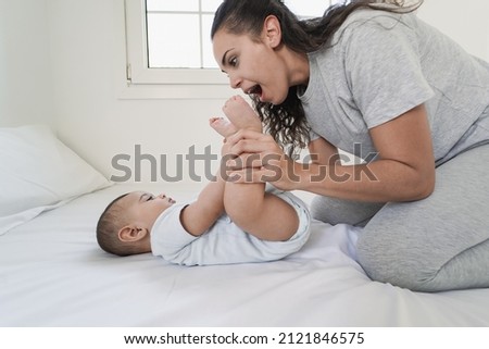 Young mother having playful time with baby at home on bed