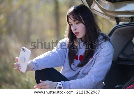 Portrait of a beautiful girl outdoors who uses a smartphone, shares digital content with each other and enjoys taking a selfie picture.