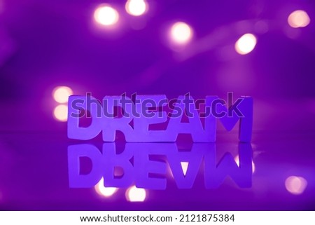 Dream word on a purple background with lights 