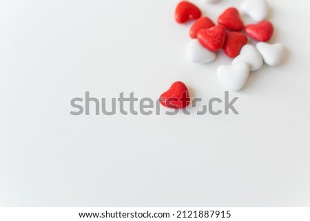 Valentine's day pattern background flat lay top view of red and white heart shaped candies scattered on white background. Selective focus, noise. Place for an inscription