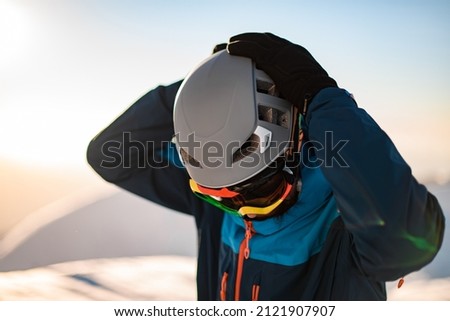 close-up of gray ski helmet on the head of skier which he holds with his hands