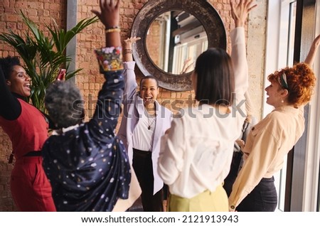 Multi ethnic mixed age range businesswomen cheering in support of International Women's Day Royalty-Free Stock Photo #2121913943