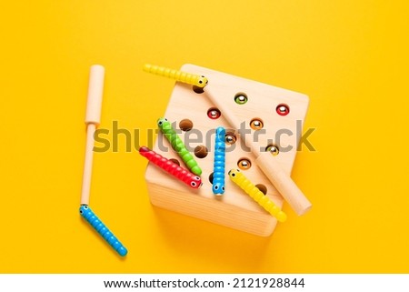 Multi-colored magnetic worms on a yellow background. Wooden children's educational toys.
