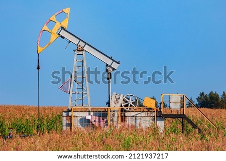 The old oil pump in a field under blue sky
