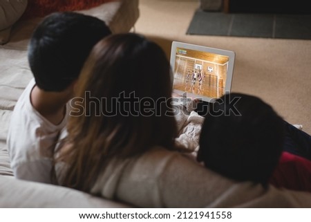 Back view of latin mother and children at home watching basketball game on laptop. sports, competition, entertainment and technology concept digital composite image.