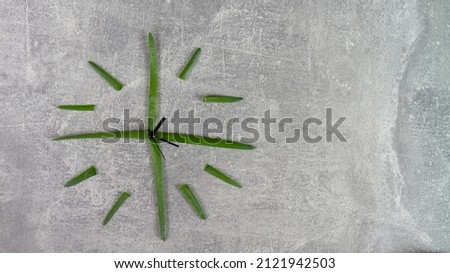 A clock made of green onion leaves shows the time.