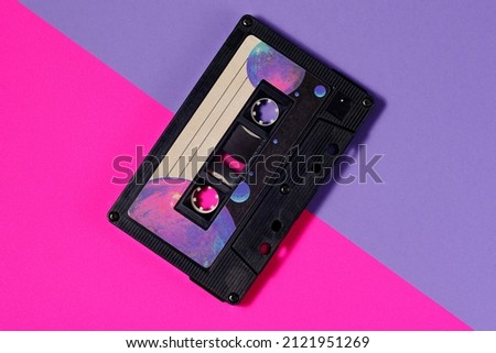 Vintage audio cassette isolated in diagonal position. Pink and purple background with diagonal. Stylish background