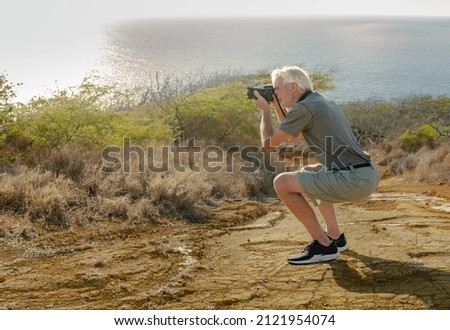 A senior handsome caucasian man taking a photo outdoor of the seascape moutain view.