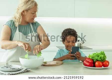 Mom and her son with phones on kitchen