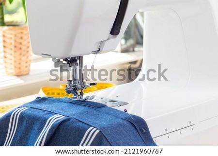 Sewing machine with striped blue white fabric and thread, home crafting or hobby, horizontal