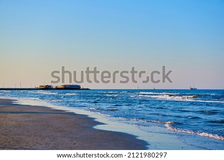 Adriatic sea, pier with people, sunset, waves and landscape.  Rimini, Italy.