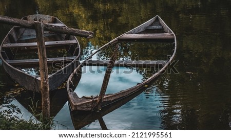 two boats half submerged in water reflect sky trees