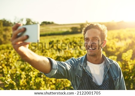 All about that farm life. Shot of a young man taking a selfie with his cellphone while working on a farm.