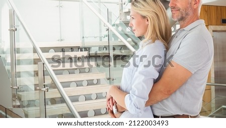 Composite image of caucasian senior couple hugging and smiling against stairs in background. love and relationship concept