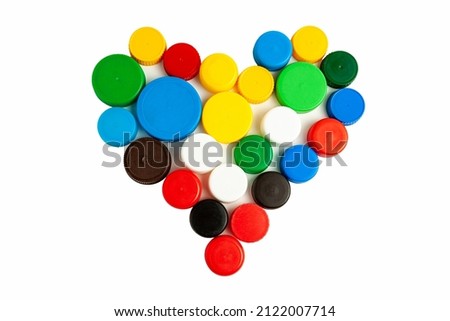 Colored screw caps for plastic bottles used to seal plastic bottles on a white background. Used bottle caps in the shape of a heart collected for plastic recycling. Separate waste sorting. Royalty-Free Stock Photo #2122007714