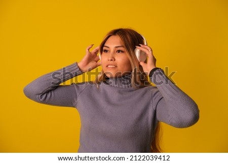 Asian-looking woman in headphones, yellow background