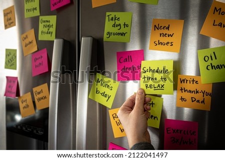 Hand Holding Schedule Time to Relax Sticky Note Memo to Fridge Door Full of Colorful Reminders Royalty-Free Stock Photo #2122041497