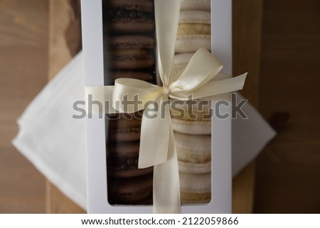 A box of macaron, a white gift box with a satin ribbon on a wooden table. Delicious french macaroons. A large element.