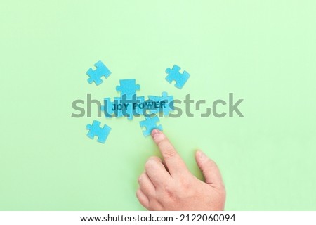 A man connecting the puzzle pieces with the words Joy Power. The concept of positive thinking, self-development and joy of life.