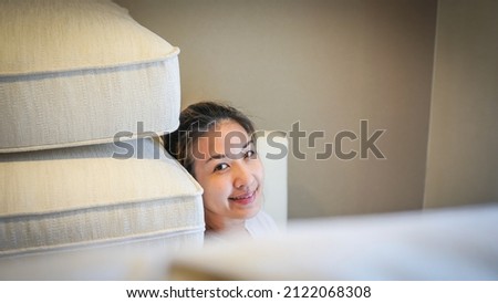 Woman lying down on sofa with smiling face and looking at camera. Apartment living concept. Domestic life.