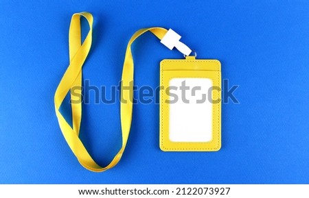 Blank white badge in a yellow case with a yellow drawstring on a blue background