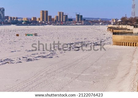 The Amur River on the border between China and Russia in winter. Border Patrol ski track on snowy ice. The city of Heihe is in the background. View from the embankment of the city of Blagoveshchensk.