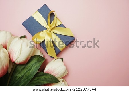 Blue Gift boxes with gold ribbon and tulip flower bouquet on pink background