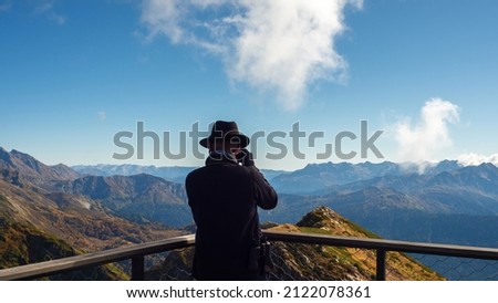 A photographer in the mountains, a traveler in a hat takes a photo of a beautiful mountain panorama