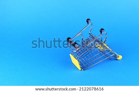 Empty upside down shopping cart on blue background 