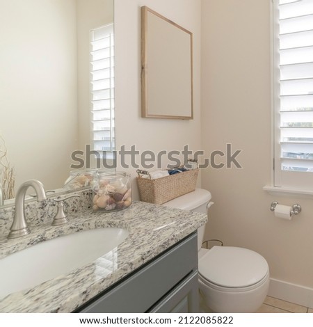 Square Interior of a bathroom with woven basket and wooden picture frame