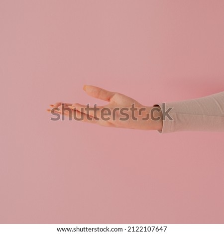 women hand against pastel pink background. modern minimalism with copyspace