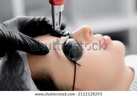 Laser removal of permanent makeup eyebrow of young woman in salon. Royalty-Free Stock Photo #2122128293