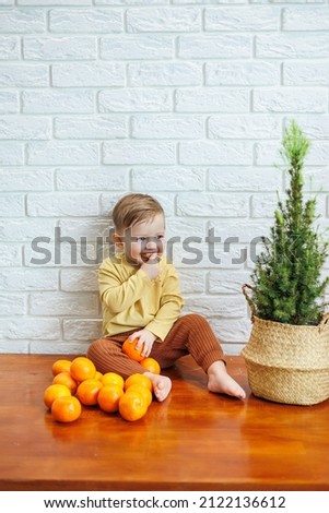 Cute smiling kid eating one fresh juicy tangerine