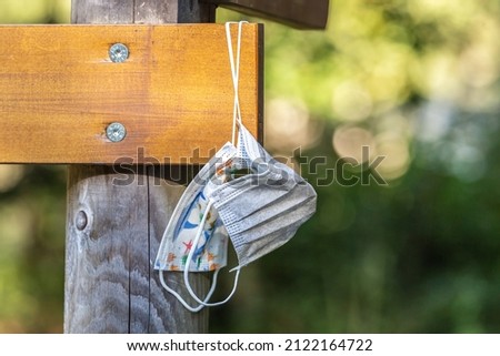 Close-up of forgotten corona face masks hanging on a signpost outdoors Royalty-Free Stock Photo #2122164722
