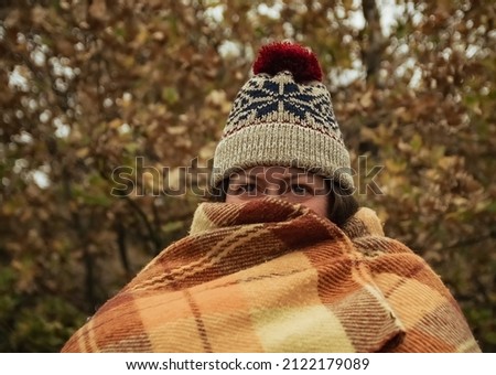 Portrait of a woman in a hat and a plaid on the background of autumn trees.
