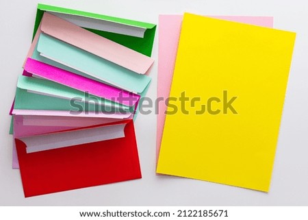 Multicolored envelopes with blank yellow sheet of paper, greeting card or invitation mockup