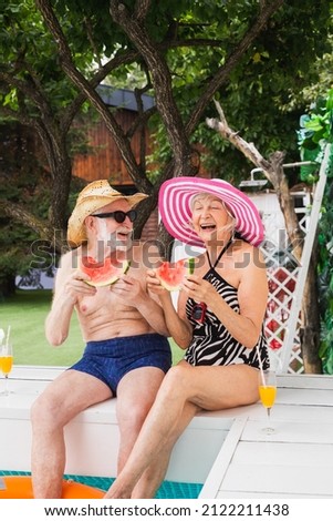 Happy senior couple having party in the swimming pool - Elderly friends releaxing at a pool party during summer vacation Royalty-Free Stock Photo #2122211438