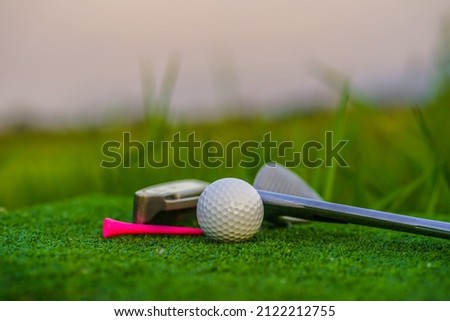 Golf balls and golf clubs  on a green lawn in a beautiful golf course with morning sunshine. The ball at the hole on the golf course.                               
