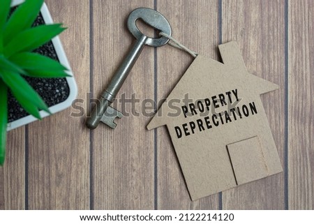 Property depreciation text on house model and key on wooden desk Royalty-Free Stock Photo #2122214120