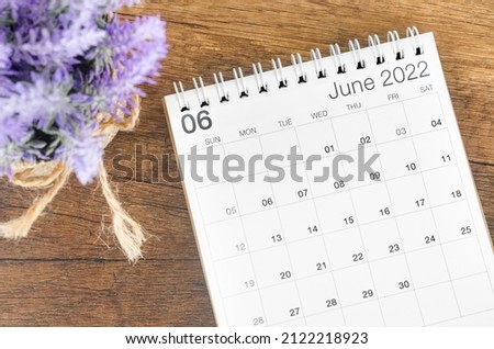 The June 2022 desk calendar with flower on wooden background.