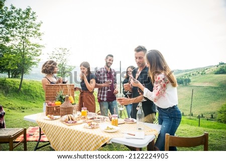 Group of young happy friends having pic-nic outdoors - People having fun and celebrating while grilling ata barbacue party in a countryside Royalty-Free Stock Photo #2122224905