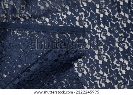 Folded navy-colored lace fabric texture background. This fabric is made of 100% polyester and stretchy.