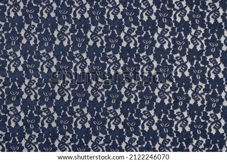 Flat navy-colored lace fabric texture background. This fabric is made of 100% polyester and stretchy.