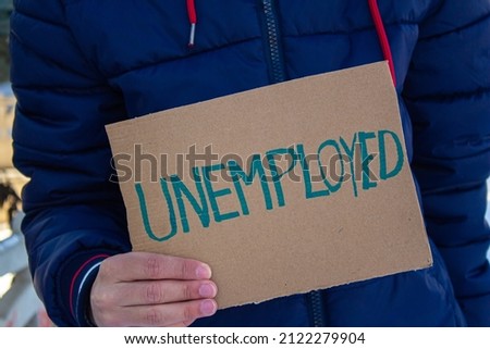 Man holding sign board with inscription UNEMPLOYED. Concept of losing job and looking a new one. He is having financial problems and needs a job.