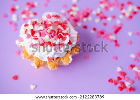 cake with whipped cream studded with small hearts on a purple background. Valentine's day and birthday concept